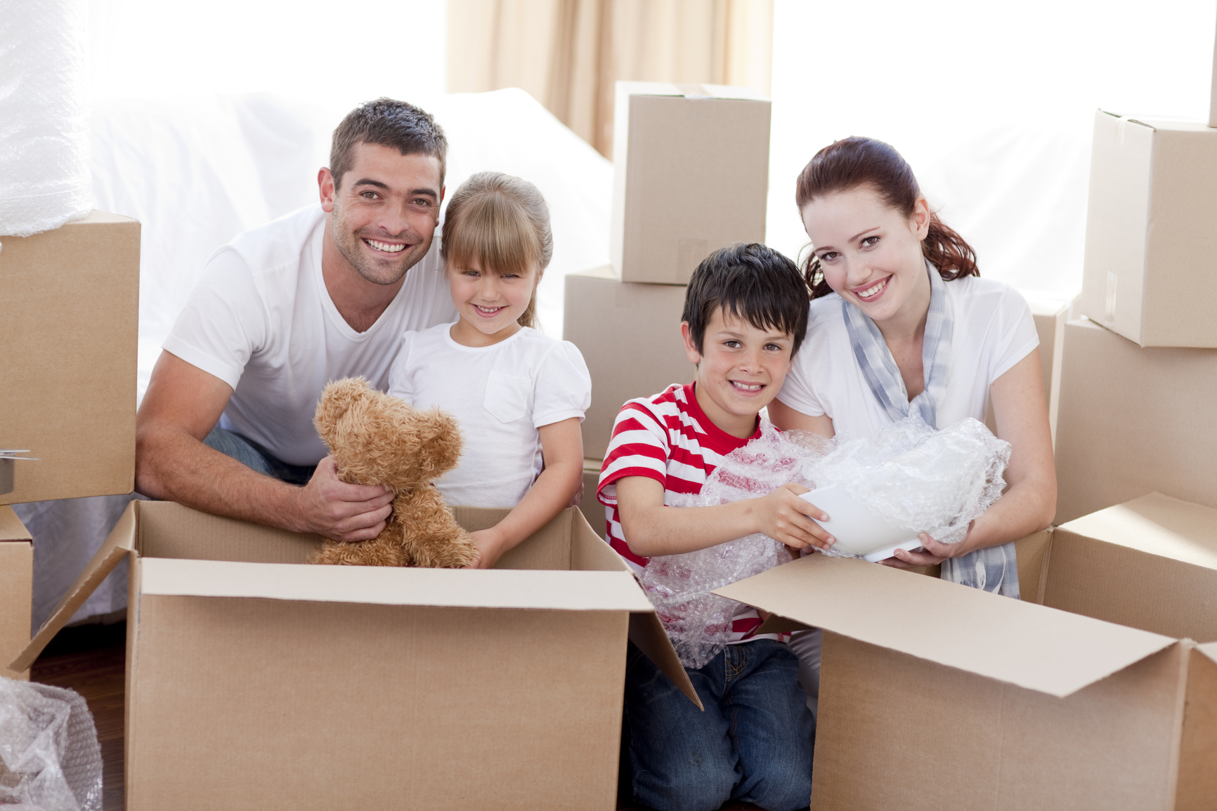 Family Opening Moving Boxes and Smiling