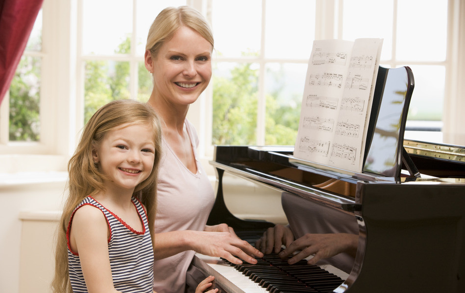 Woman and Young Daughter Smiling Playing Piano