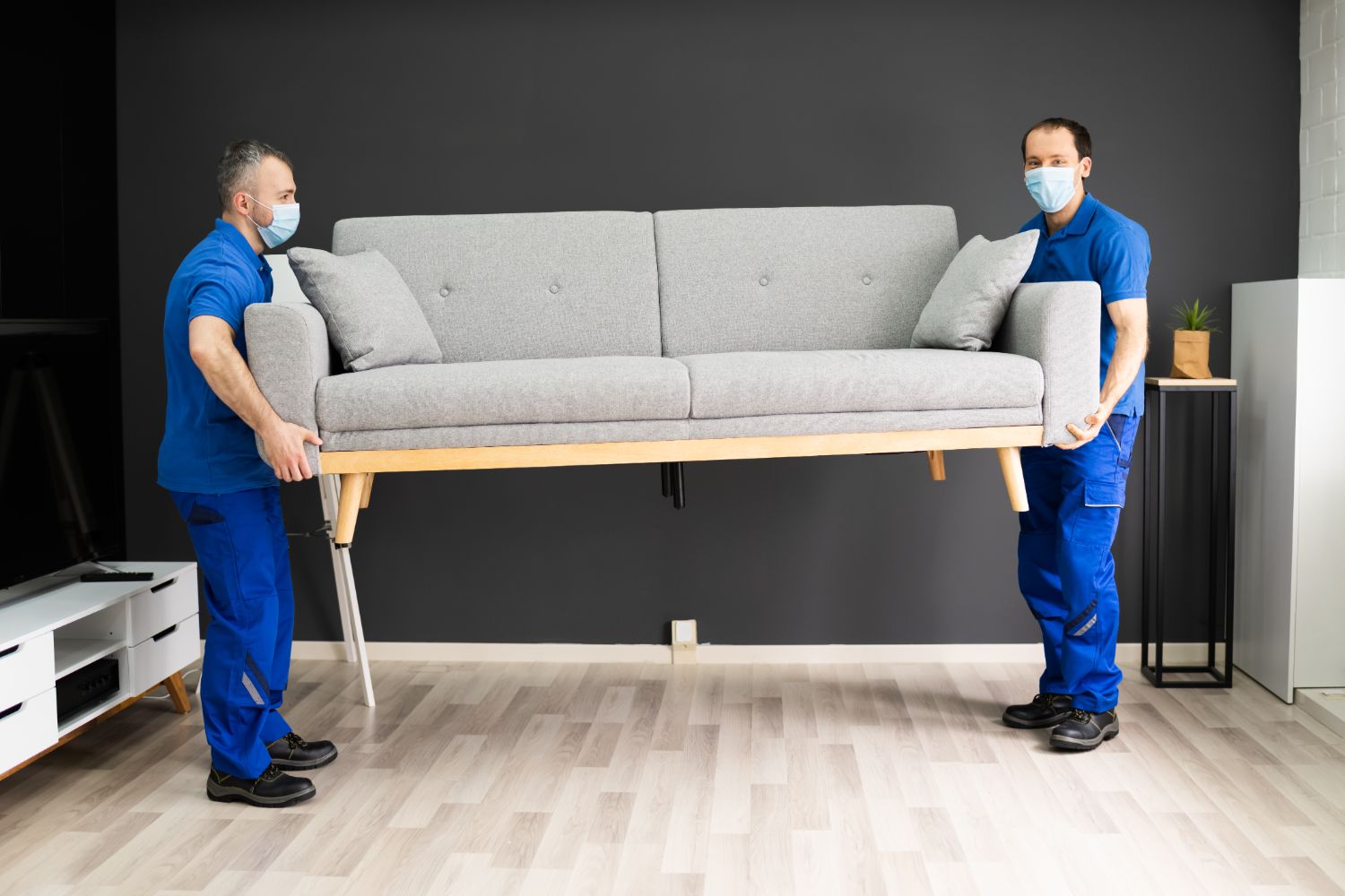COVID safe movers wearing masks lifting a couch