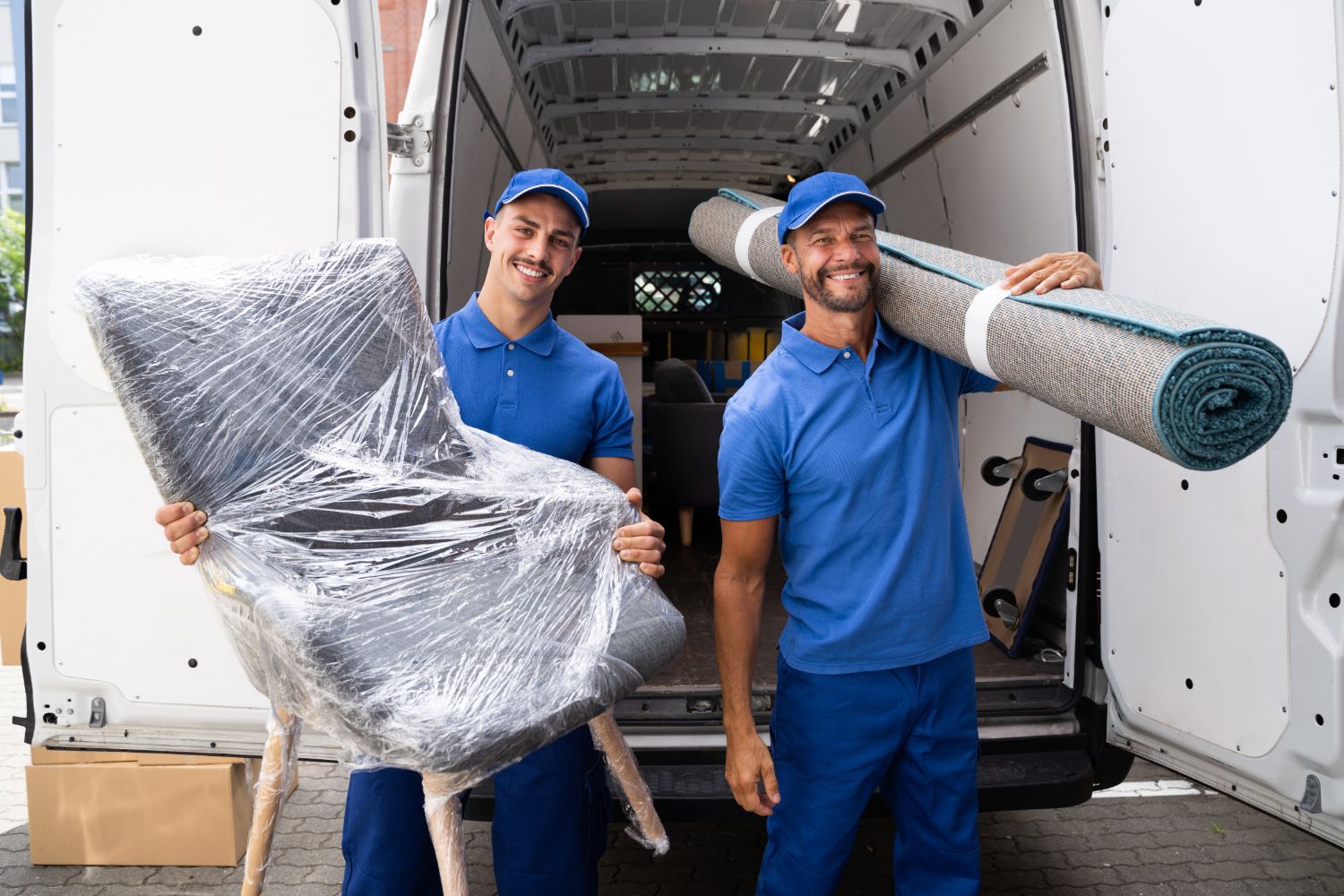 Smiling movers loading chair and rug into moving truck
